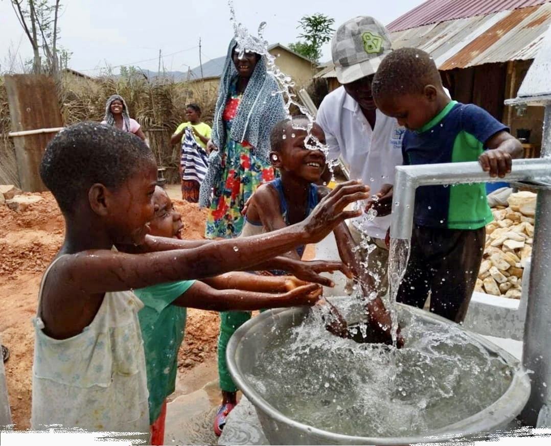 "Children playing with water from a community well in Africa"