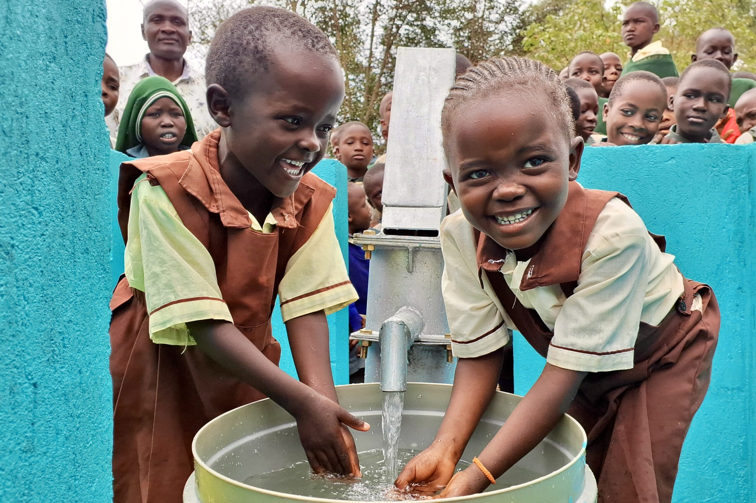 Happy African children playing with clean water next to a new community water well.