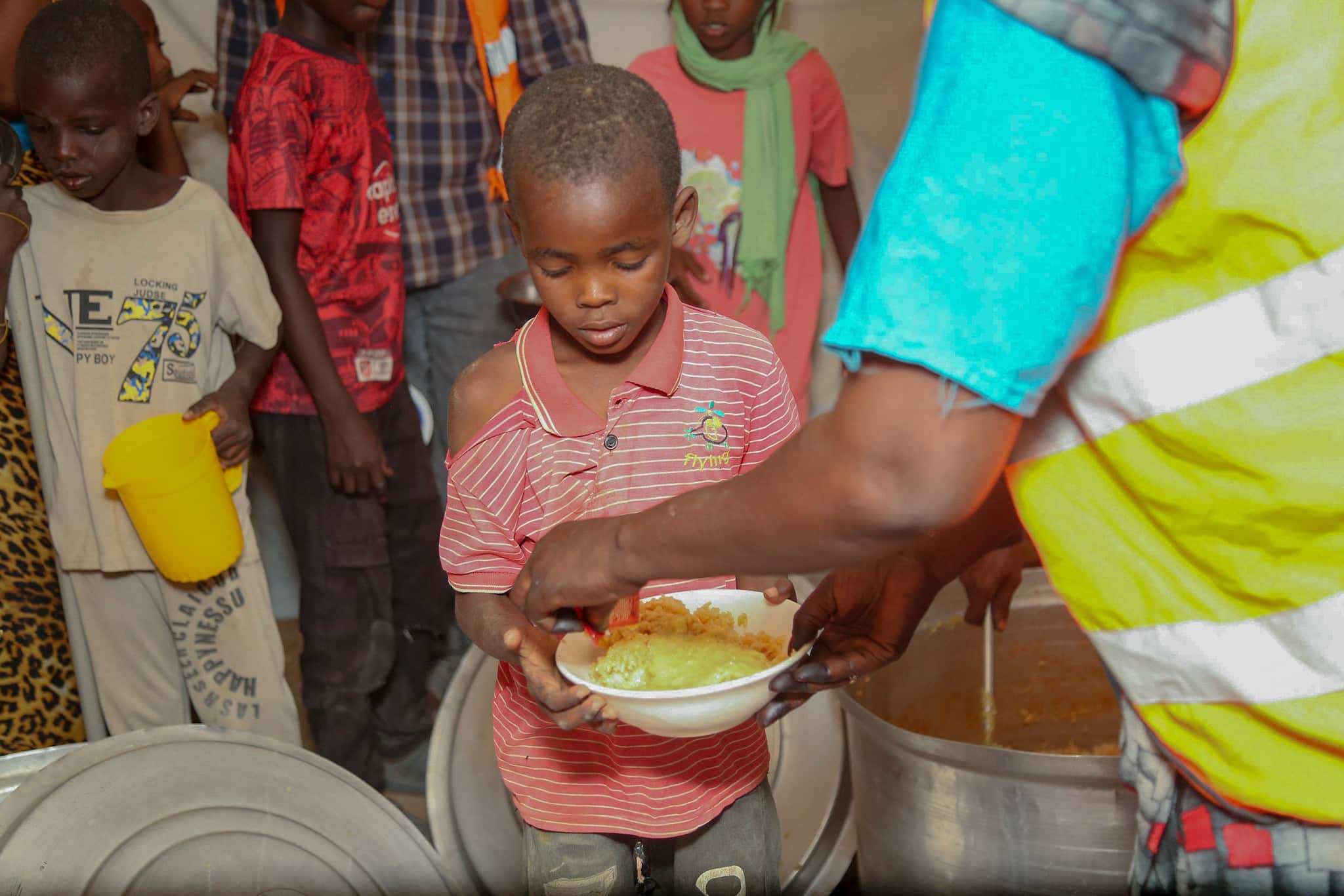 A Barakah Charity worker serves a hot meal to a young boy in Sudan.